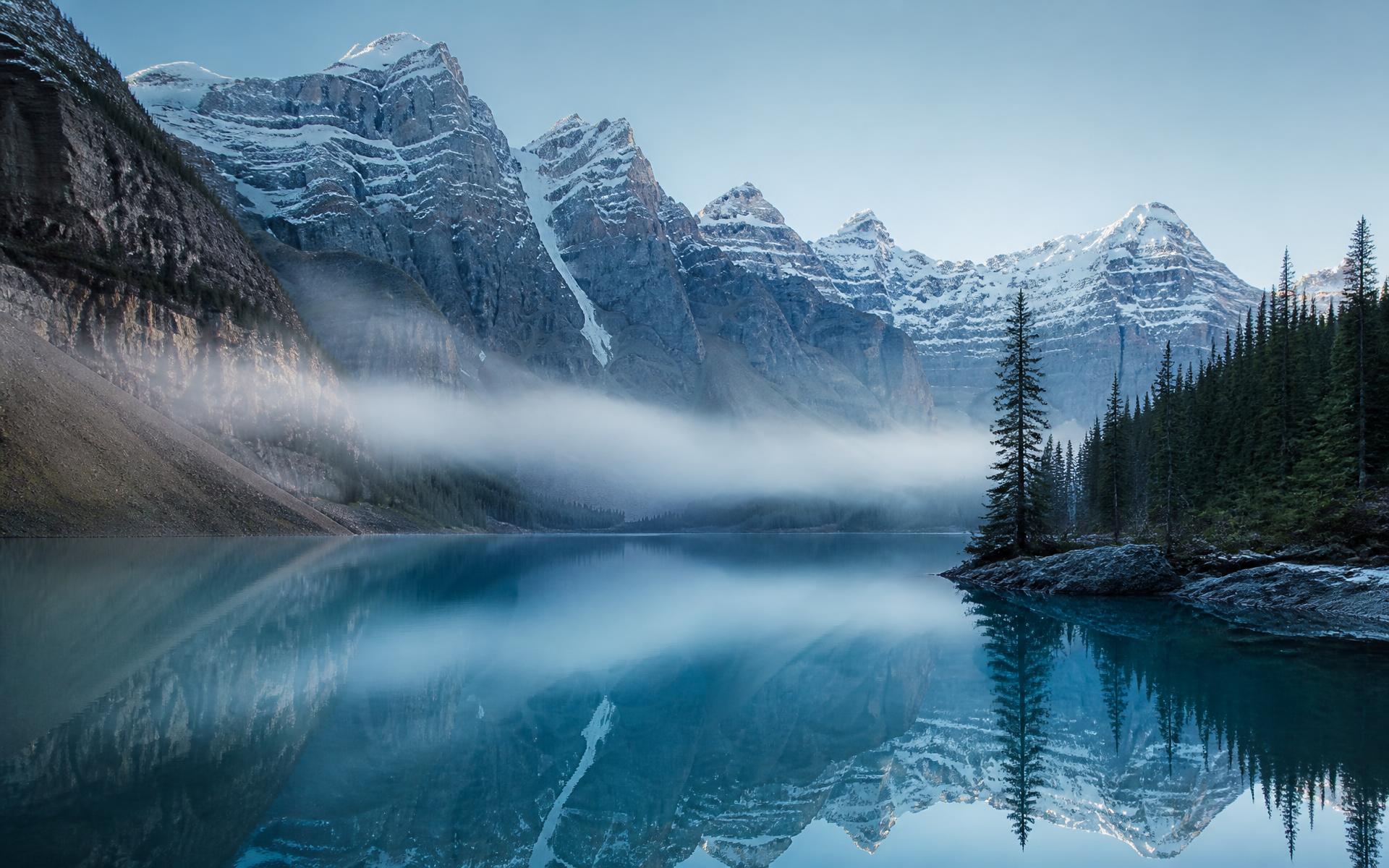 Glacial lake beneath snow-covered Canadian mountains at first light